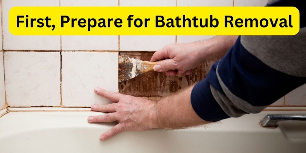 A-man-using-a-spatula-to-remove-tile-from-a-wall-next-to-a-bathtub